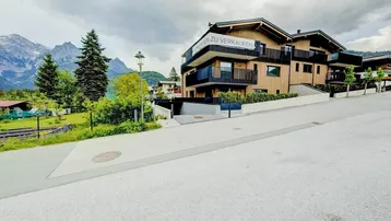 Modernes Gebäude mit Holzfassade und Balkonen in alpiner Berglandschaft.