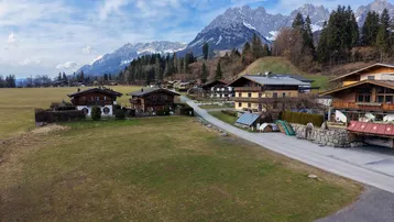 Panoramablick auf eine ländliche Siedlung mit traditionellen Häusern vor einer beeindruckenden Bergkulisse.