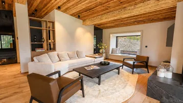 Geräumiges Wohnzimmer mit Holzbalkendecke, bequemen Sofas und einem gemütlichen Fensterplatz.