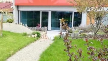 Wind- und sichtgeschützte Terrasse mit großen Glasfronten und einem kleinen Gartenbereich.