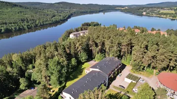 Luftaufnahme der Wohngebäude in waldreicher Umgebung mit weitem Blick auf den See.