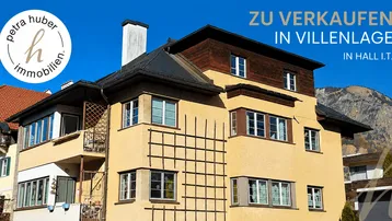 Gelbe Fassade eines Hauses in Villenlage mit Blick auf die Berge und blauen Himmel.