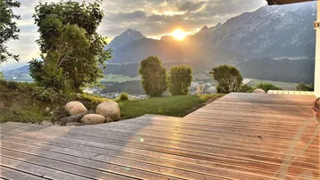 Geräumige Holzterrasse mit atemberaubendem Bergblick bei Sonnenuntergang, ideal zum Entspannen.