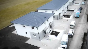 Luftaufnahme einer Reihe von Neubauhäusern in der Bauphase mit umliegendem Feld.