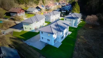 Luftaufnahme einer Siedlung mit mehreren modernen Einfamilienhäusern in grüner Umgebung.