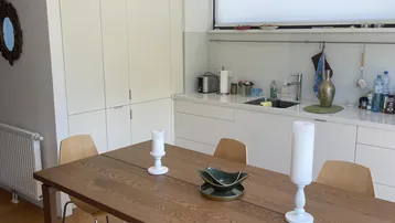 Helle, moderne Küche mit weißen Schränken, Holztisch und offenem Essbereich.