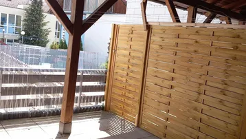 Überdachter Außenbereich mit Holzbalken und Sichtschutz, bietet einen Blick auf die Umgebung.