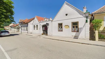 Historisches Gebäude mit weißer Fassade und traditionellen Fenstern an einer ruhigen Straße.