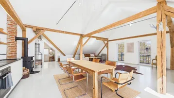 Heller Essbereich im Dachgeschoss mit Holztisch, modernen Stühlen und Blick ins Grüne.