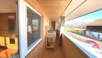 Langer Holzbalkon mit Bergblick und viel Sonnenschein, ideal zum Entspannen im Freien.