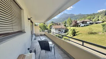 Geräumiger Balkon mit Fliesenboden, Sitzgelegenheiten und weitem Bergblick.