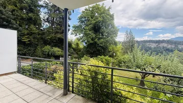 Geräumiger Balkon mit Fliesenboden und weitem Blick ins Grüne und auf die umliegende Landschaft.
