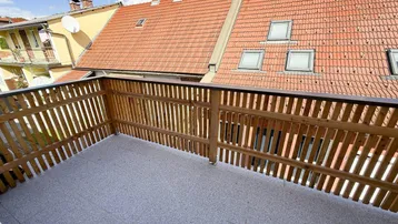 Geräumiger Balkon mit Holzgeländer und Fliesenboden, bietet einen schönen Blick auf die Umgebung.