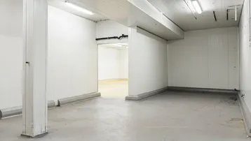 Großer, leerer Lagerraum mit weißen Wänden, Betonboden und sichtbaren Säulen, bereit zur Nutzung.