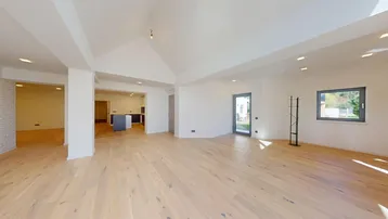 Helles, offenes Wohnzimmer mit Holzboden, hohen Decken und Zugang zum Außenbereich.