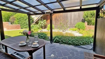 Überdachte Terrasse mit Esstisch und Blick auf den gepflegten Garten.
