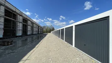 Reihe von Garagenboxen im Bau mit Gerüst an einem angrenzenden Gebäude.