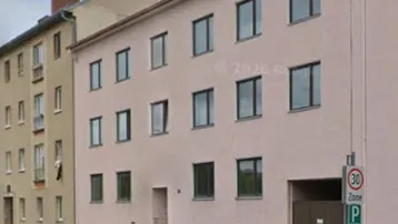 Mehrstöckiges Wohngebäude mit schlichter Fassade an einer städtischen Straße.