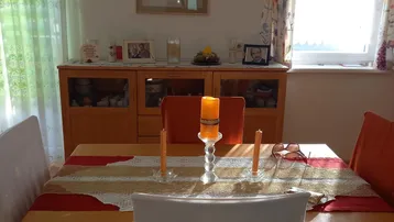 Gemütlicher Essbereich mit Holztisch, Stühlen und einem Sideboard, hell durch Fenster.