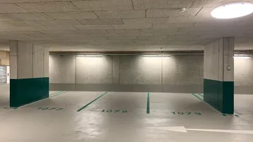 Helle Tiefgarage mit nummerierten Stellplätzen, Betonwänden und effizienter Beleuchtung.