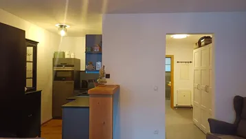 Offener Wohnbereich mit Holzboden, der in eine moderne Küche übergeht und einen Blick in den Flur bietet.