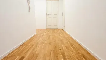 Heller Flur mit Holzboden und weißen Wänden, der zu verschiedenen Räumen führt.