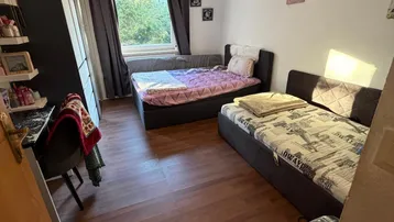 Helles Schlafzimmer mit zwei Einzelbetten, Holzfußboden und Blick ins Grüne.