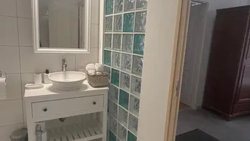 Modernes Badezimmer mit Waschbecken, Spiegel und dekorativer Glasbausteinwand.