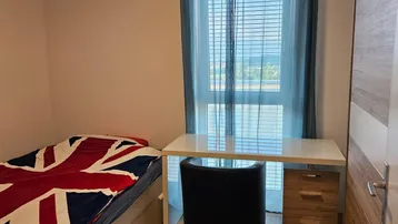 Gemütliches Schlafzimmer mit Einzelbett, Schreibtisch und Fenster mit Blick ins Grüne.