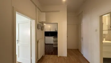Heller Flur mit Holzfußboden und Zugang zu Küche und Badezimmer.