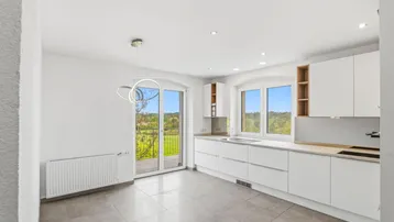 Helle, moderne Küche mit weißen Schränken, Fliesenboden und Zugang zum Balkon mit Weitblick.