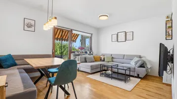 Helles Wohn- und Esszimmer mit Holzboden, bequemer Sitzecke und Zugang zum Balkon.