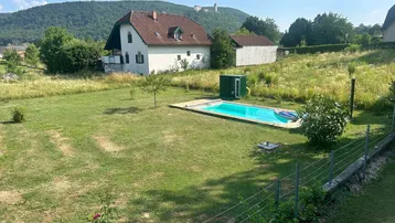 Großzügiger Gartenbereich mit Pool, umgeben von grüner Landschaft und Blick auf eine historische Burg.