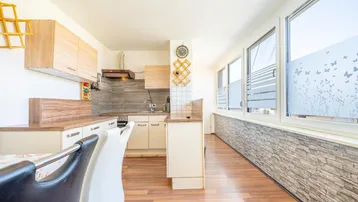 Helle Küche mit Laminatboden, Holz-Arbeitsplatten und großen Fenstern mit dekorativer Folie.