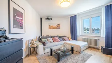 Helles Wohnzimmer mit bequemer Eckcouch, Projektor und Blick auf die Stadt.