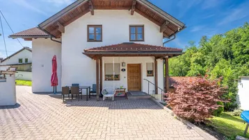 Traditionelles Einfamilienhaus mit gepflasterter Auffahrt und überdachtem Eingangsbereich.