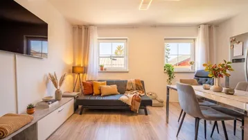 Heller offener Wohn- und Essbereich mit modernem Sofa, Esstisch und Holzboden.