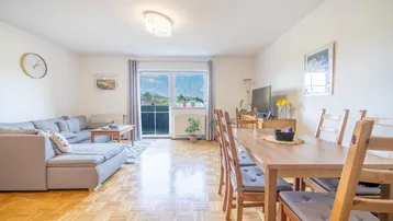 Heller Wohn- und Essbereich mit Parkettboden und Zugang zum Balkon, bietet eine gemütliche Atmosphäre.