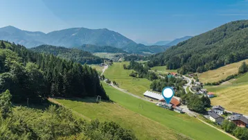 Panoramablick auf die umliegende Berglandschaft und grüne Täler mit einem markierten Standort.