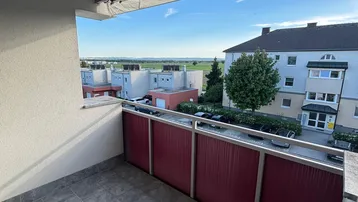 Geräumiger Balkon mit Fliesenboden und weitem Blick über die Umgebung und grüne Felder.