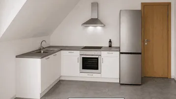 Moderne Küche im Dachgeschoss mit weißen Einbauschränken, grauer Arbeitsplatte und neuen Geräten.