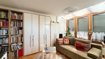 Helles Wohnzimmer mit bequemer Couch, Bücherregal und praktischen Einbauschränken.