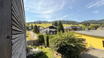 Weitläufiger Blick vom Balkon auf grüne Hügel und die umliegende Landschaft.