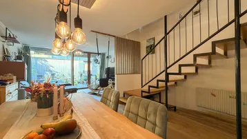 Moderner Essbereich mit Holztisch, Designerleuchten und offener Treppe zum Wohnbereich.