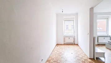 Heller, leerer Raum mit Parkettboden und Fenster, bereit zur individuellen Gestaltung.
