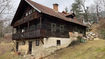 Rustikales Holzhaus mit traditionellem Satteldach und Balkon in ländlicher Umgebung.
