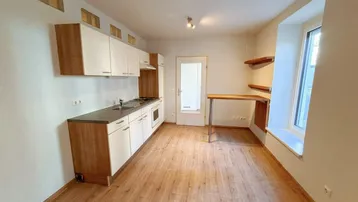 Helle, offene Küche mit Laminatboden, Einbauküche und integriertem Essbereich am Fenster.
