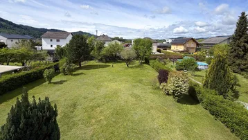 Großer, gepflegter Garten mit Rasenfläche und Blick auf die umliegende Wohngegend von oben.