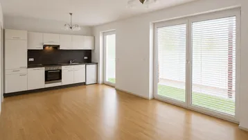 Helle, offene Küche mit weißen Schränken, Holzboden und Zugang zu großen Fenstern.