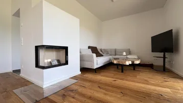 Gemütliches Wohnzimmer mit Holzboden, modernem Kamin und bequemer Sitzecke.